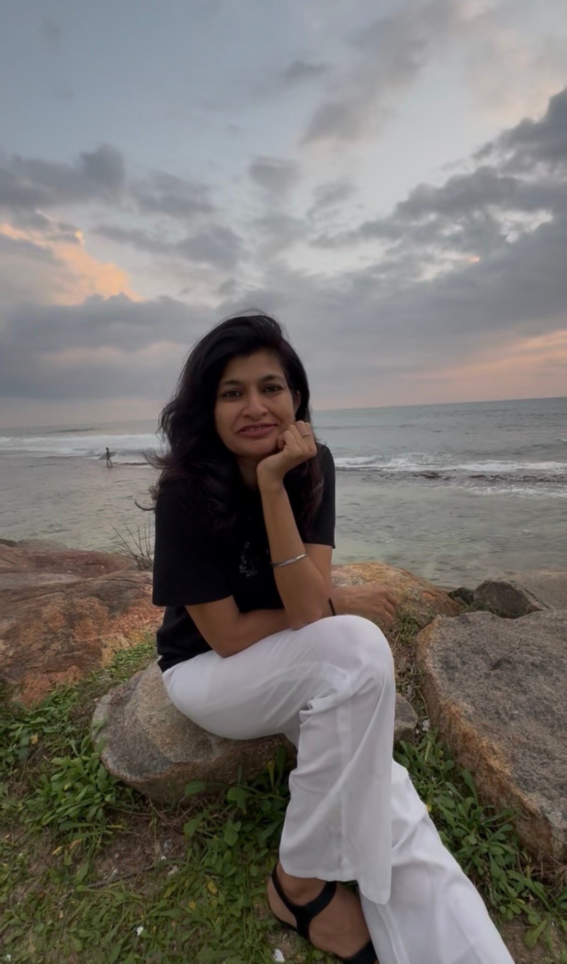 Portrait of Naz Chougley seated by the sea at sunset